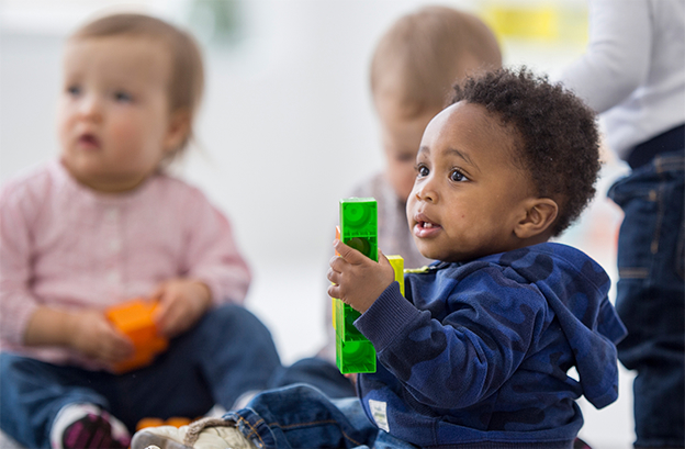 A group of infants holding colorful toy blocks.