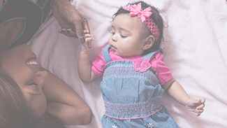 A young smiling black mom holds her baby